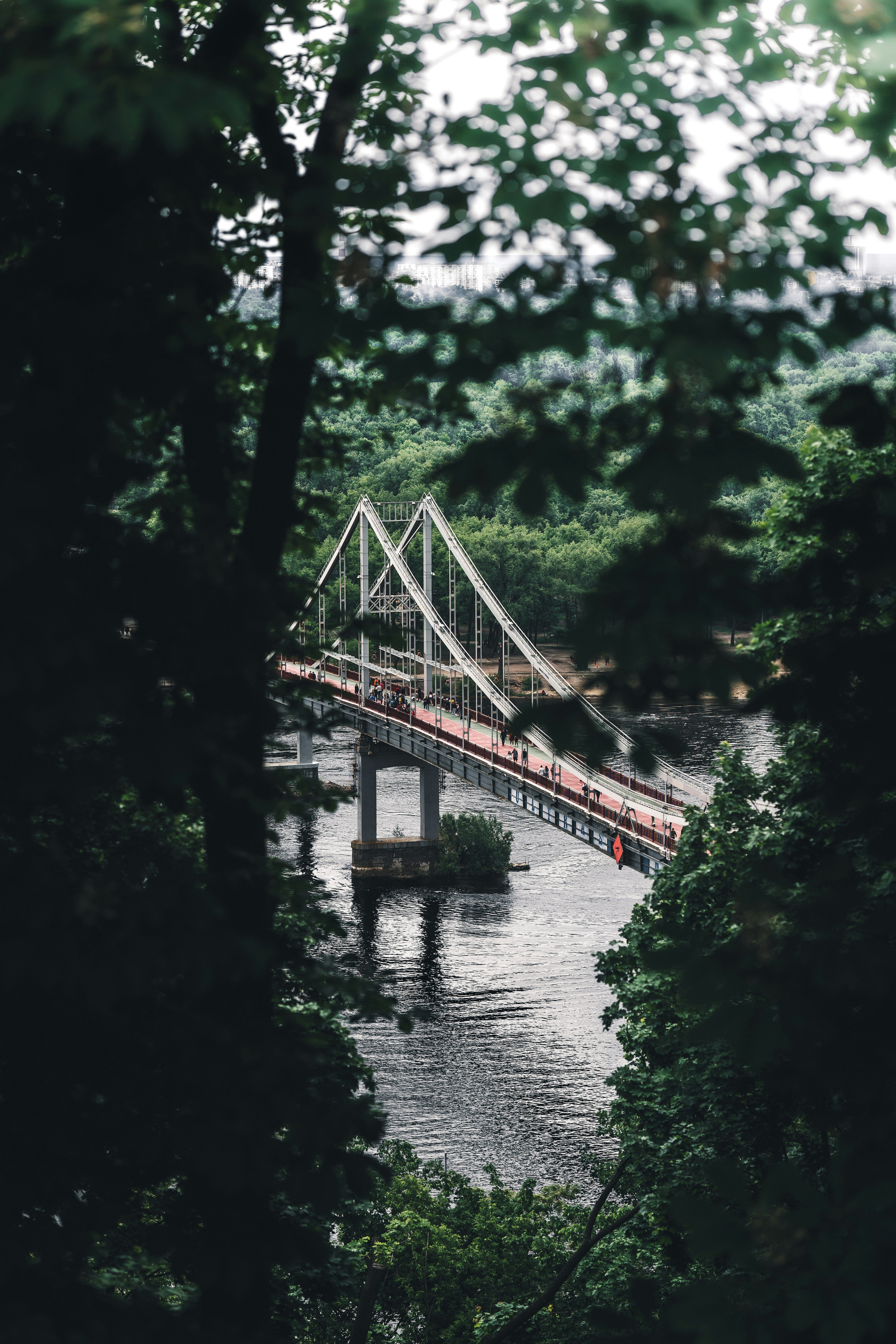 brown wooden bridge over river surrounded by green trees during daytime